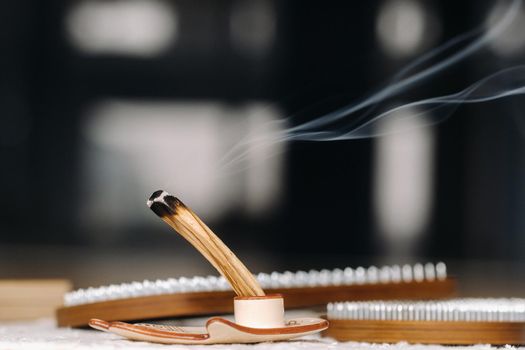 A smoking Palo Santo stick and boards with nails for yoga classes.