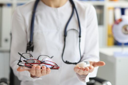 Close-up of female doctor making choice between contact lenses and glasses. Ophthalmologist, ophthalmology and vision correction concept