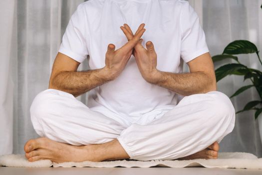 a man in white sportswear is doing yoga with a fitness room. the concept of a healthy lifestyle.