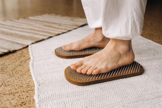 The man's feet are next to boards with nails. Yoga classes.