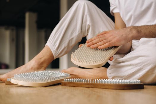 A man holds in his hands boards with nails for yoga classes.