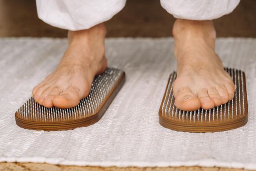 The man's feet are next to boards with nails. Yoga classes.