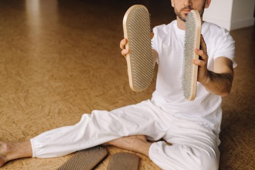 A man holds in his hands boards with nails for yoga classes.