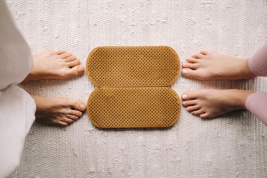 The legs of a man and a woman stand next to boards with nails for Yoga classes.