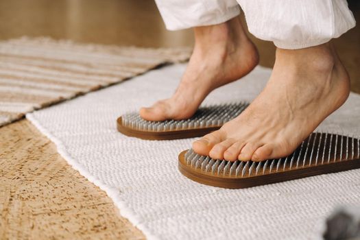 The man's feet are next to boards with nails. Yoga classes.