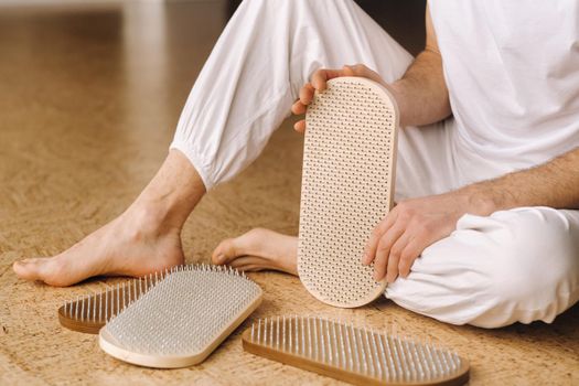 A man holds in his hands boards with nails for yoga classes.