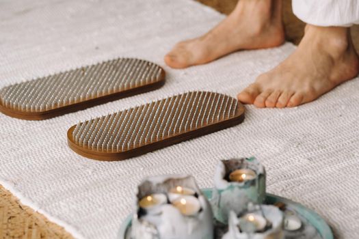 The man's feet are next to boards with nails. Yoga classes.