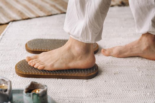 The man's feet are next to boards with nails. Yoga classes.