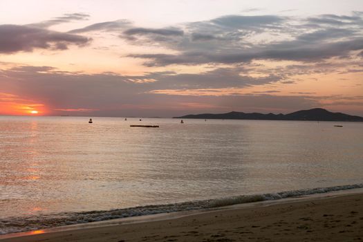 Evening beach. Pink sunset reflection in the sea.