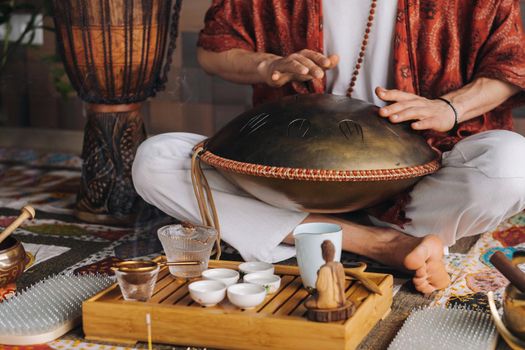 Close-up of a man's hand playing a modern musical instrument - the Orion tongue drum during the tea ceremony.