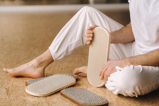 A man holds in his hands boards with nails for yoga classes.