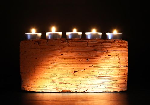 Set of lighting candles in a row against dark background