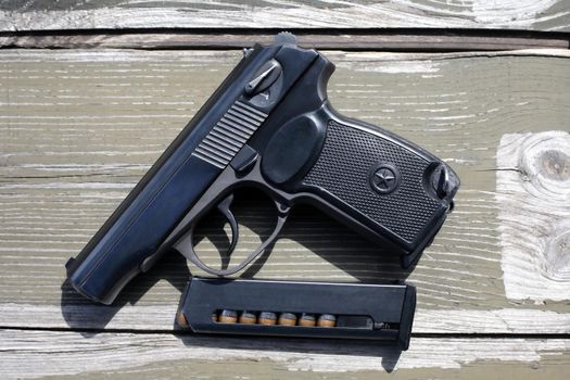 Eight-capacity magazine near handgun on wooden background