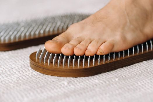 The man's feet are next to boards with nails. Yoga classes.