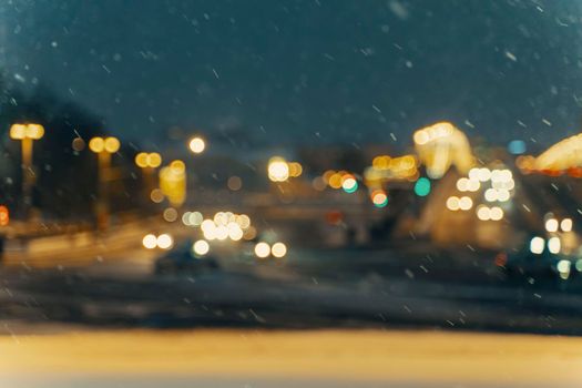 Winter blurred background with falling snow on the background of a city street.