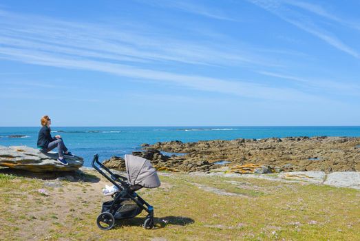 Mother strolling with a baby looks at the Atlantic Ocean