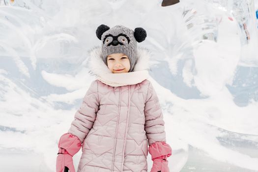 little girl in a knitted hat and scarf and ice sculptures