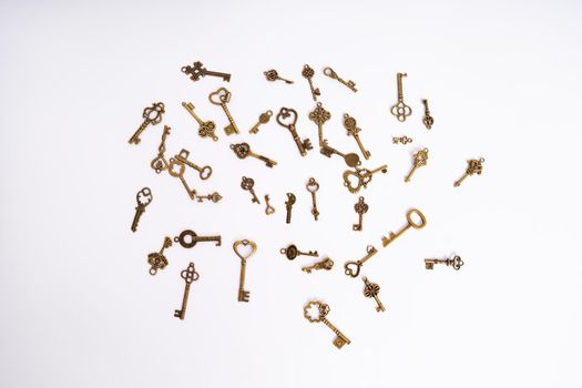 A pile of vintage golden skeleton keys isolated on white background. Golden skeleton keys in different shapes. Keys for locks and treasure boxes with unique shapes and designs.