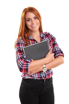 Smiling young redhead woman in plaid shirt holding a notebook in front of her, isolated on white background. Education, study, exams, achievement concept.