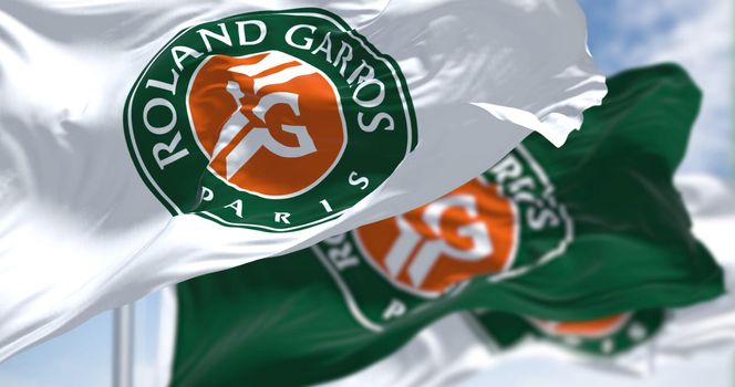 Paris, France, April 2022: three flags with the Roland-Garros logo waving in the wind. French Open is a major tennis tournament scheduled in late May each year