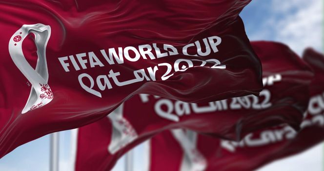 Doha, Qatar, April 2022: three flags with the Qatar 2022 Fifa World Cup logo waving in the wind. The event is scheduled in Qatar from 21 November to 18 December 2022