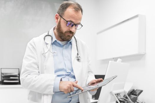 Male doctor with white coat and stethoscope using tablet, network connection in hospital room, Medical technology network concept. High quality photography.
