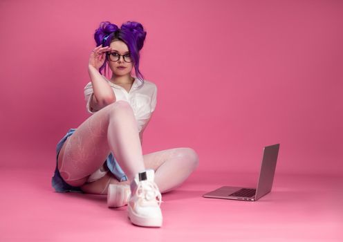 sex bright girl in summer clothes poses sexually showing underwear and stockings on the floor with a laptop