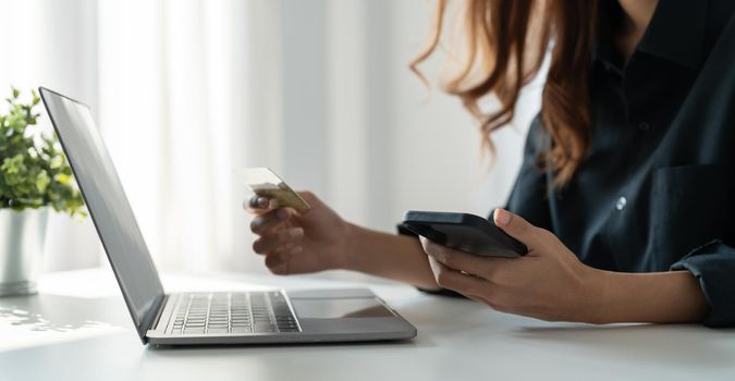 Close up of woman hold bank credit card shopping online using mobile phone, buying goods or ordering online, entering bank accounts and details in online banking offer