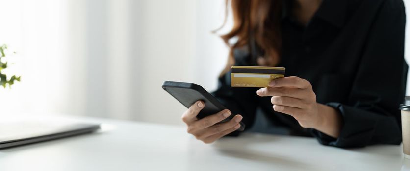 Close up of woman hold bank credit card shopping online using mobile phone, buying goods or ordering online, entering bank accounts and details in online banking offer