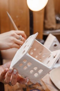 A master ceramist holds a clay product in his hands. Making a ceramic candle holder from clay. The process of coating the candlestick with glaze. Close-up.