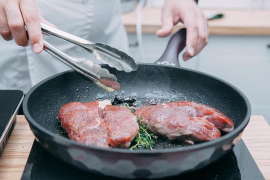 Cooking beef ribeye steak in a frying pan in the cooking class. Steak with spices. Cooking process, close-up.