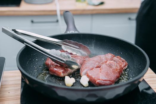 Cooking beef ribeye steak in a frying pan in the cooking class. Steak with spices. Cooking process, close-up.