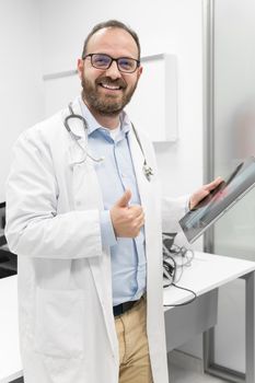 Friendly male doctor smiling and giving thumb up sign. High quality photo