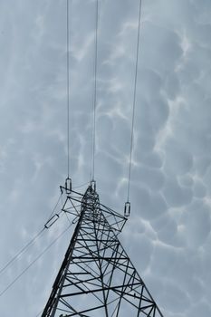 High voltage power line against a backdrop of billowing storm clouds. The forces of nature and modern electricity.