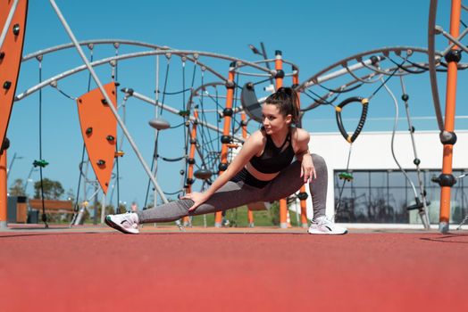 sporty girl does fitness on a sports field in the summer outdoors