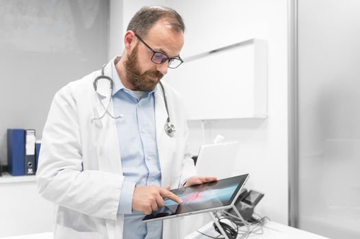 Doctor examine an x-ray image of a patient in digital tablet at doctor office. High quality photography.