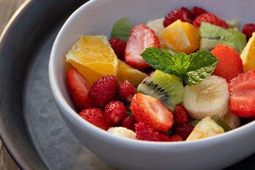 Fruit salad in a white bowl on a metal tray.