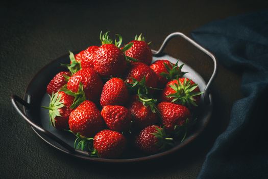 Ripe fresh farmed natural strawberries on a metal tray on the table.