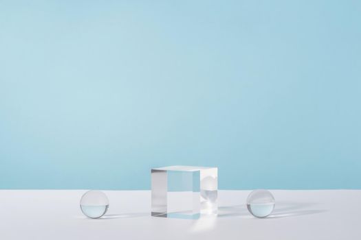 Pedestal cosmetic display glass podium platform with stylish props for product presentation, cosmetics geometric stand, mockup scene for jewellery mock up. Acrylic blocks and balls on blue background