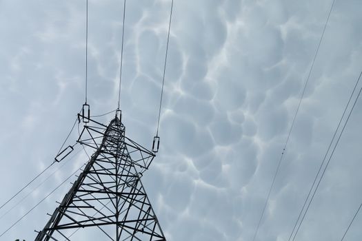 High voltage power line against a backdrop of billowing storm clouds. The forces of nature and modern electricity.