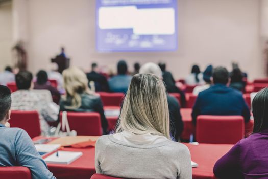 Speaker Giving a Talk at Business Meeting. Audience in the conference hall. Business and Entrepreneurship. Focus on unrecognizable people from rear.