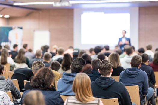 Speaker giving a talk in conference hall at business event. Audience at the conference hall. Business and Entrepreneurship concept. Focus on unrecognizable people in audience.