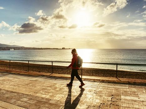 Young woman hiker with backpack on sunrise beach