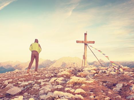 Man tourist walk to cross on the rocky mountain peak. Evening dark,colorful  sky during sunset. 