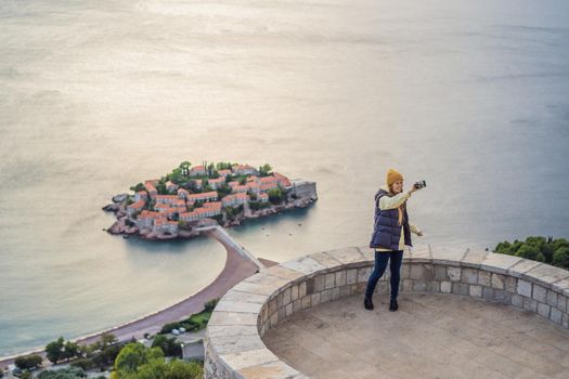 Woman tourist on background of beautiful view of the island of St. Stephen, Sveti Stefan on the Budva Riviera, Budva, Montenegro. Travel to Montenegro concept.