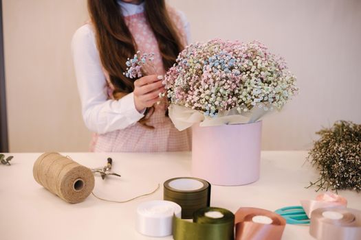 Woman make spring bouquet. Female florist wrapping beautiful bouquet of spring flowers in pack paper on the table. Beautiful flower composition