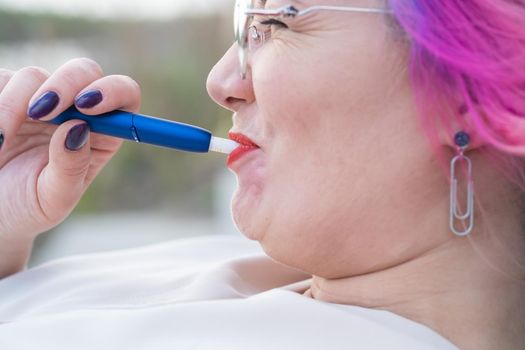 Caucasian woman with colored hair smokes an electronic cigarette