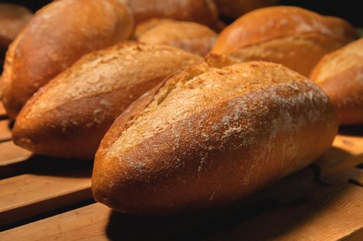 Fresh crispy hot delicious craft artisan bread. Many loaves lie on a wooden pallet.