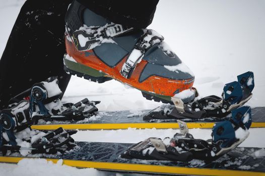 Close-up of freeride ski boots on snow. Skitour concept. Used worn boots on a male skier against the background of a glacier in cloudy weather in the mountains.