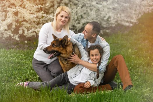 Outdoor portrait of happy young family playing in spring park under blooming tree, lovely family having fun in sunny garden.